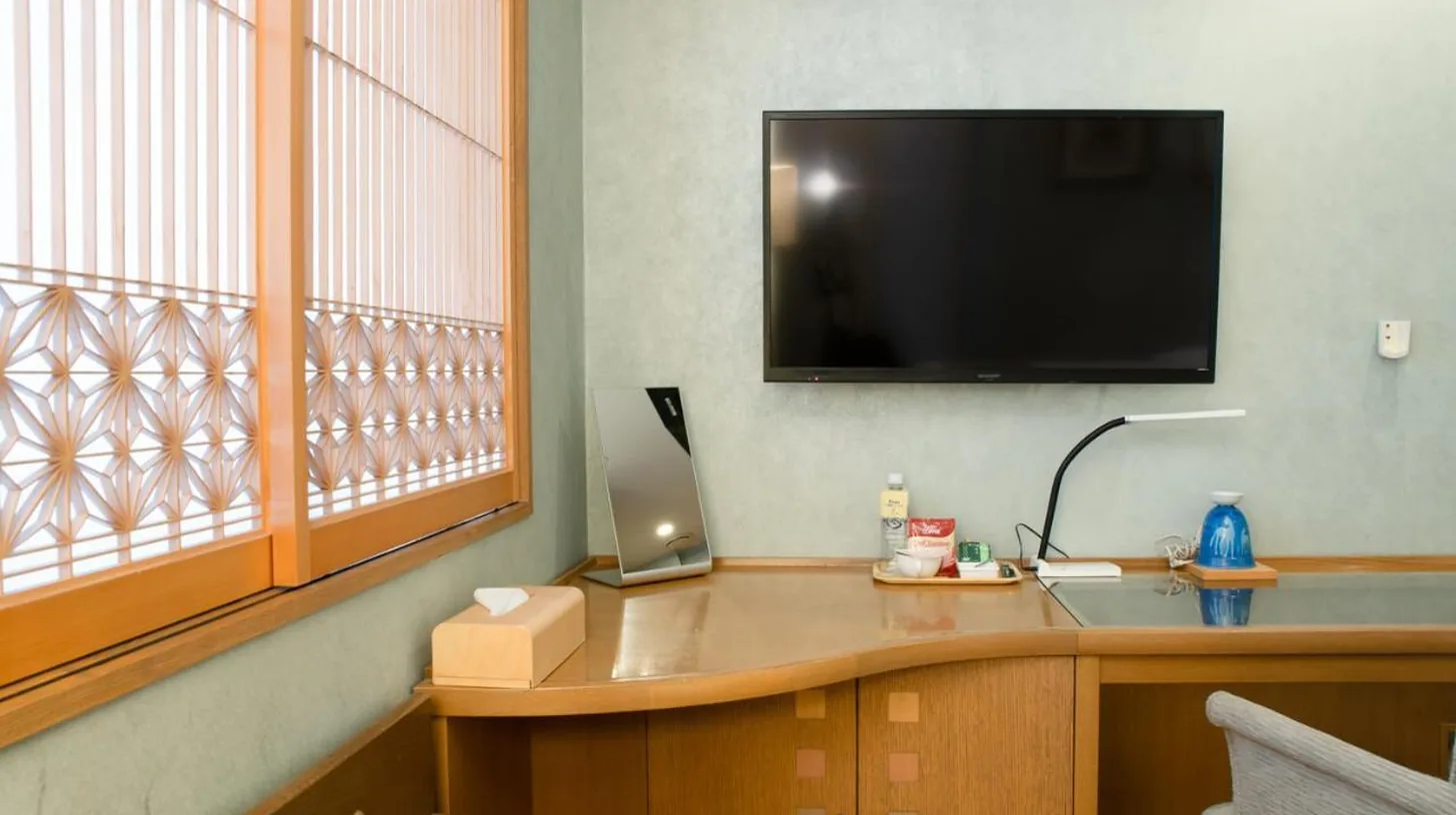 une chambre avec un bureau et une télévision sur le mur à ホテルピュリッツァー自由が丘 à Tokyo