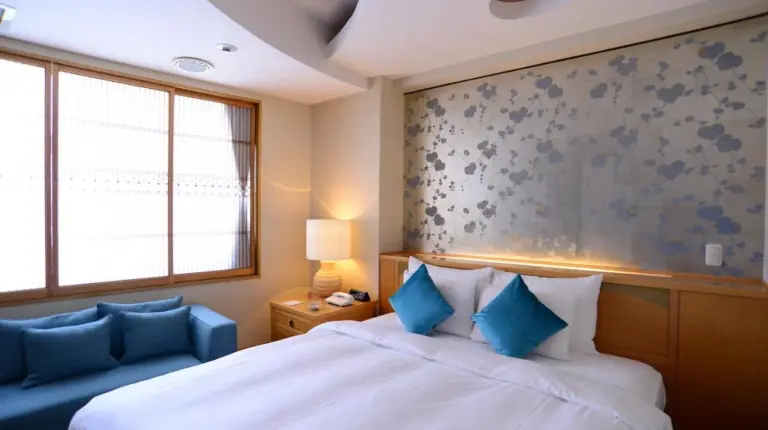 une chambre avec un grand lit et un canapé bleu à ホテルピュリッツァー自由が丘 à Tokyo