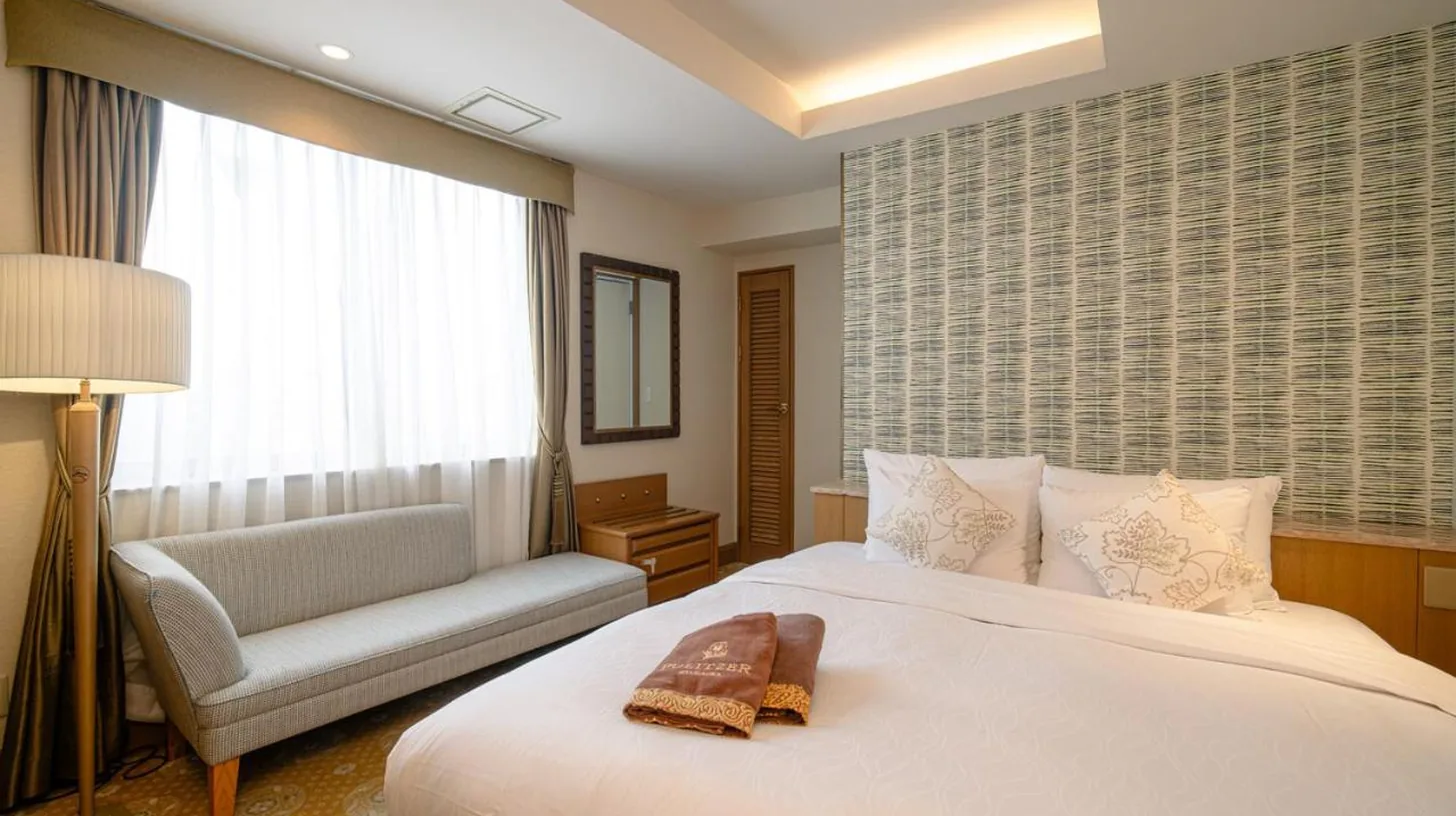 une chambre avec un grand lit blanc et un canapé à ホテルピュリッツァー自由が丘 à Tokyo