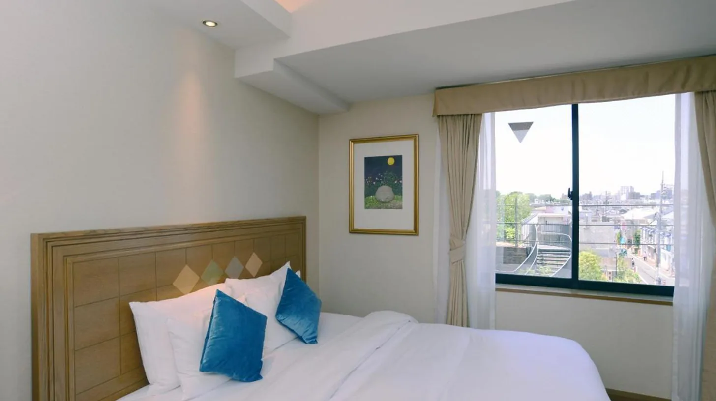 une chambre avec un lit, des oreillers bleus et une fenêtre à ホテルピュリッツァー自由が丘 à Tokyo