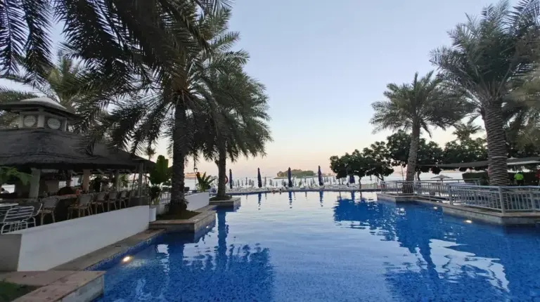a large swimming pool with palm trees and blue water at 2 Bedroom beach front apartment in Dubai