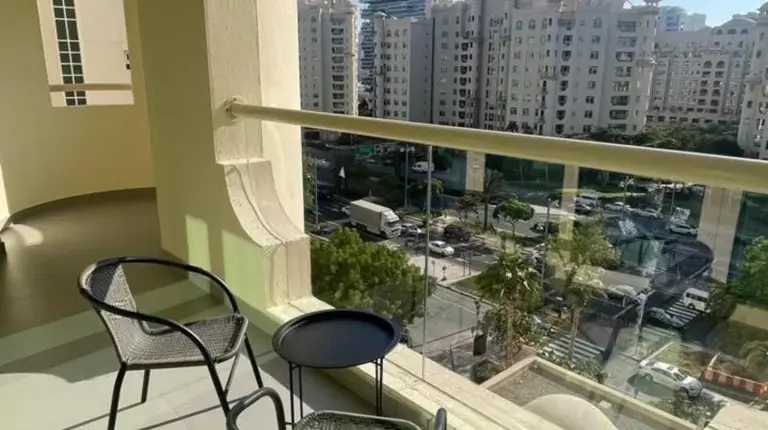 a balcony with two chairs and a view of a city at 2 Bedroom beach front apartment in Dubai