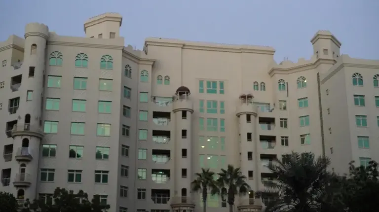 a large building with palm trees in front of it at 2 Bedroom beach front apartment in Dubai