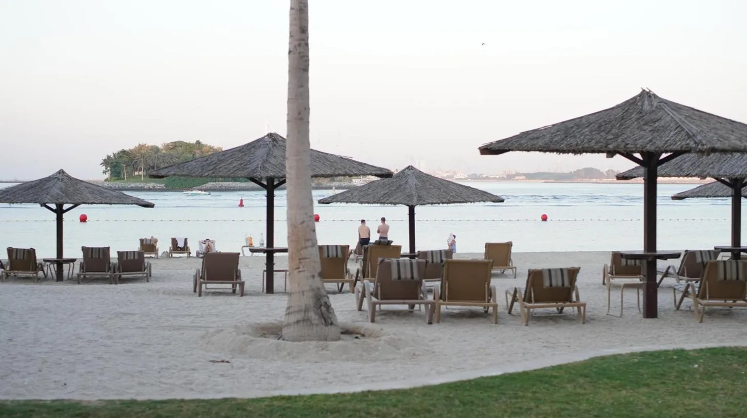 a beach with chairs and tables and umbrellas at 2 Bedroom beach front apartment in Dubai