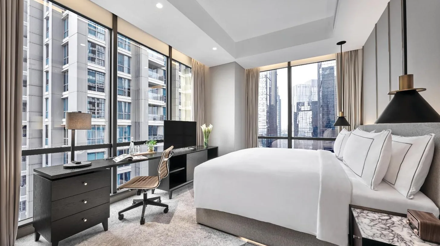 a bedroom with a bed and a living room with a view at 25hours Hotel Jakarta The Oddbird in Jakarta
