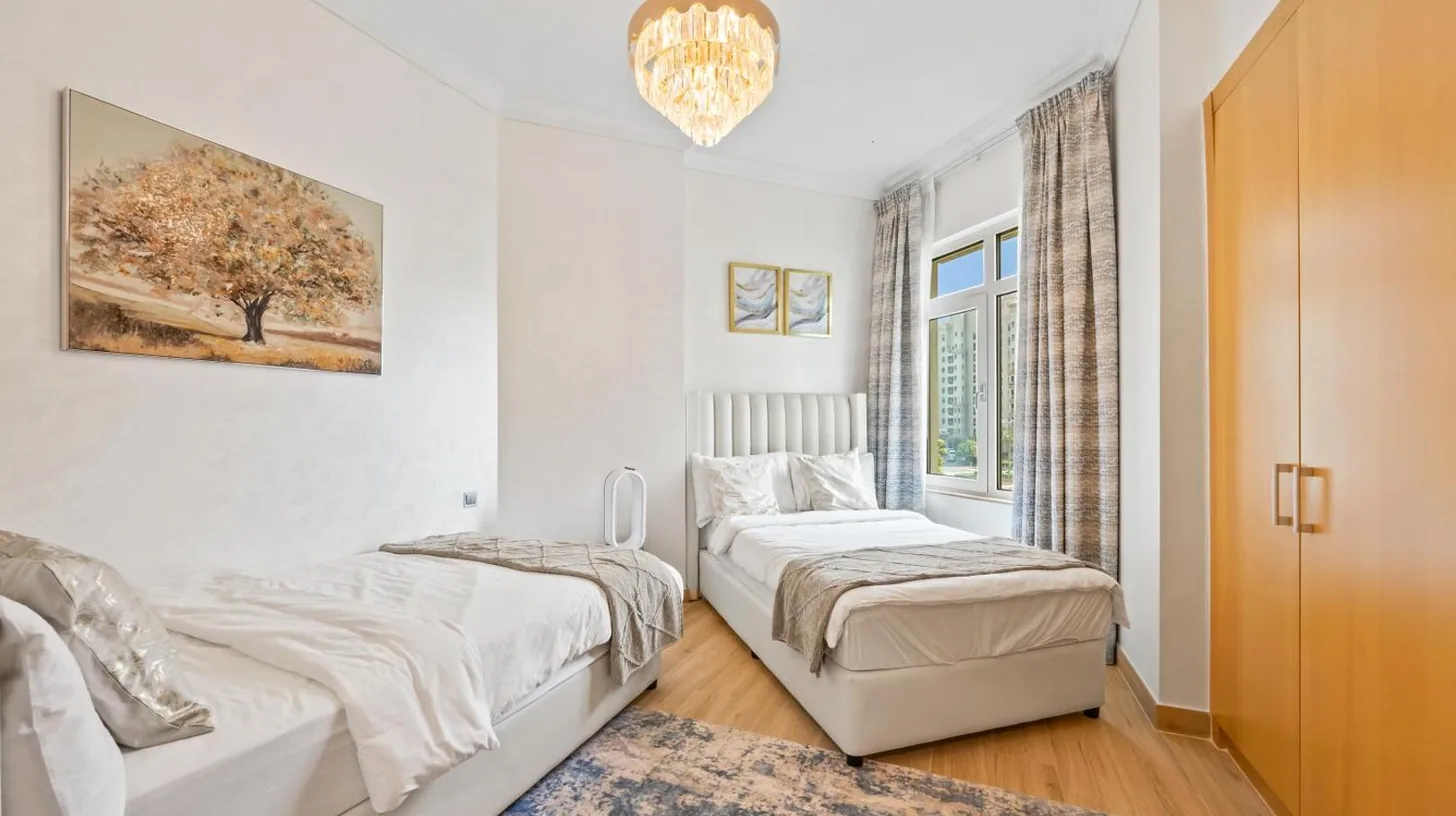 a bedroom with two beds and a chandelier at 2BDR Luxury Apartment in Palm in Dubai