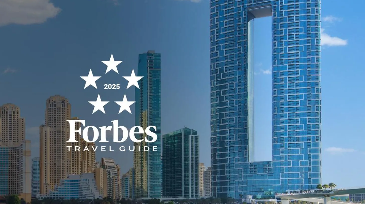 a boat in the water in front of a tall building at Address Beach Resort in Dubai