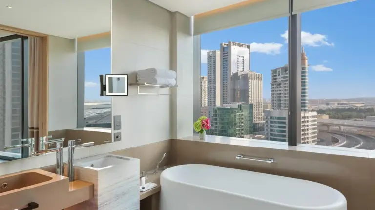 a bathroom with a large white tub and a large window at Address Beach Resort in Dubai