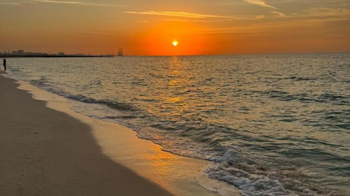a sunset on a beach with the ocean at Ajman Luxurious Holiday Homes in Ajman