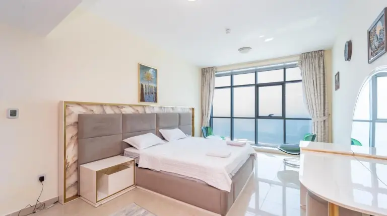 a bedroom with a bed and a large window at Ajman Luxurious Holiday Homes in Ajman