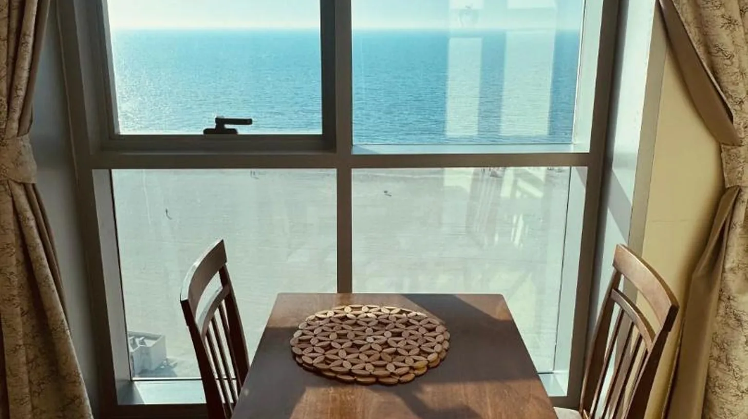 a table and chairs in a room with a large window at Ajman Luxurious Holiday Homes in Ajman