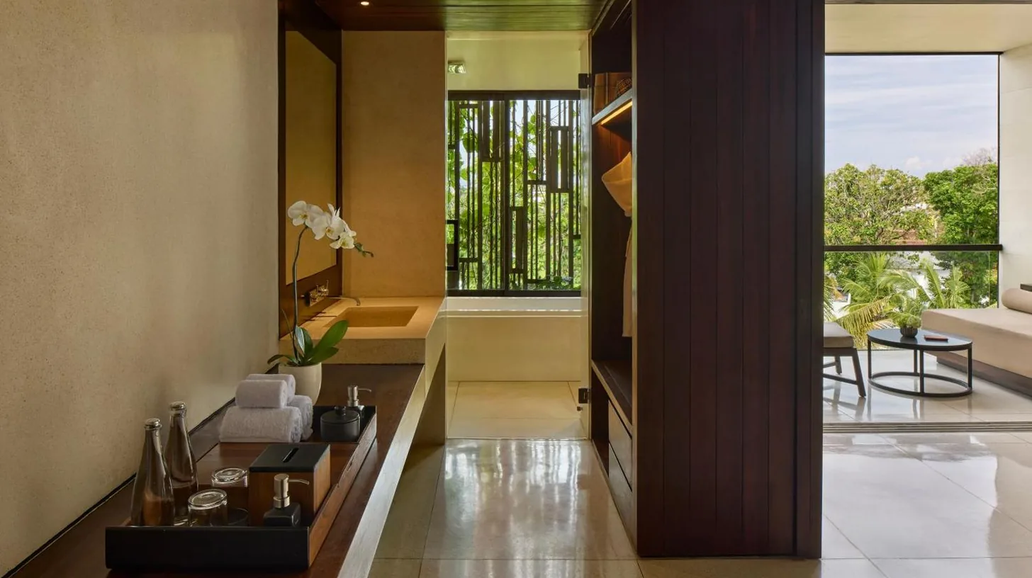 a bedroom with a bed and a living room with a couch at Alila Seminyak in Seminyak