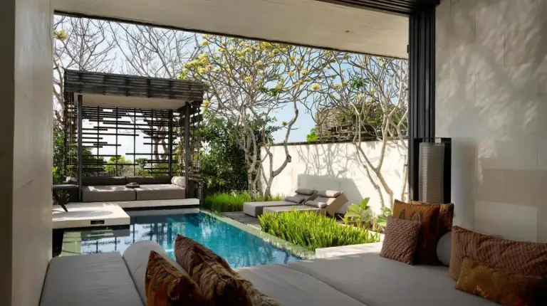 a person standing in the water next to a swimming pool at Alila Villas Uluwatu in Uluwatu