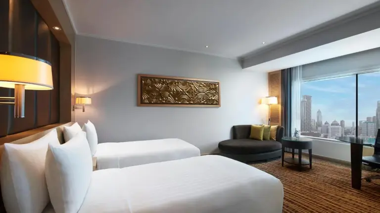a hotel room with two beds and a window at Amari Bangkok in Bangkok