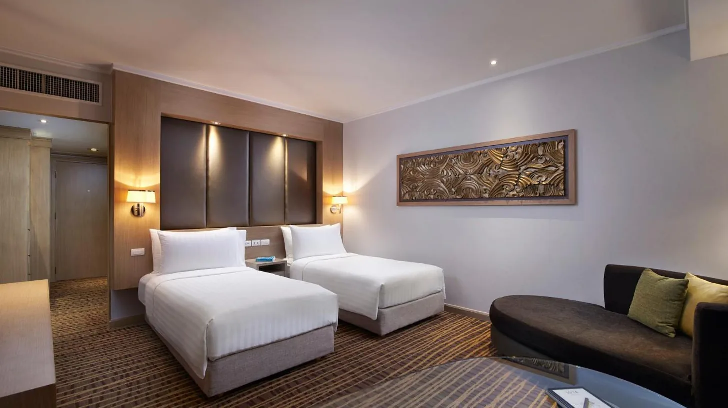 a hotel room with a couch and a desk and a window at Amari Bangkok in Bangkok