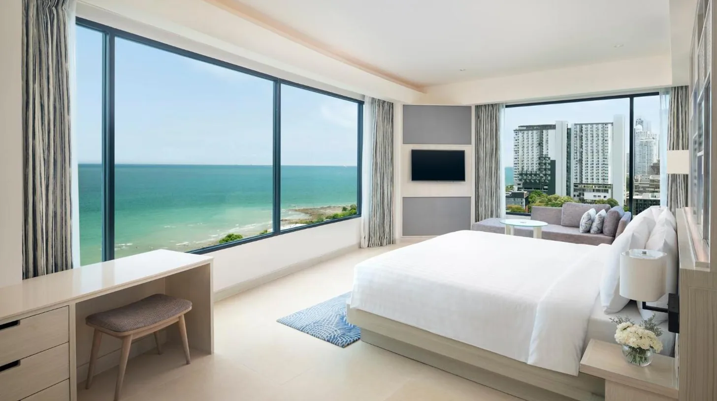 dormitorio con cama, escritorio y gran ventana en Amari Pattaya en Pattaya Central