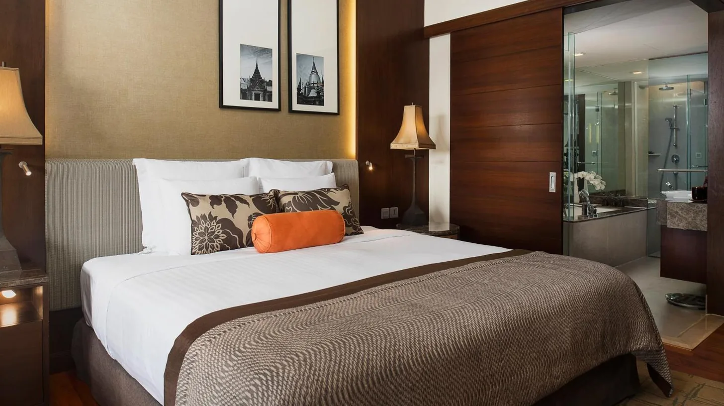 a hotel room with a large bed and a bathroom at Anantara Riverside Bangkok Resort in Bangkok