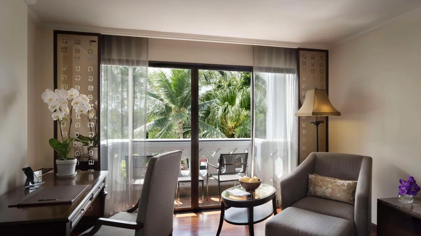 a living room with a desk and a table and chairs at Anantara Riverside Bangkok Resort in Bangkok