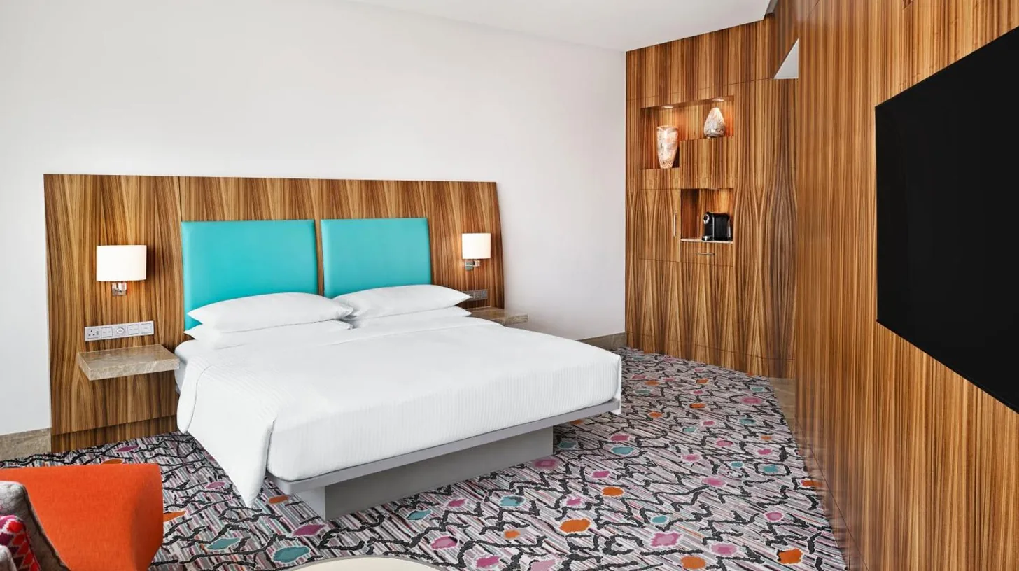 a bedroom with a large bed and a flat screen tv at Andaz Capital Gate Abu Dhabi