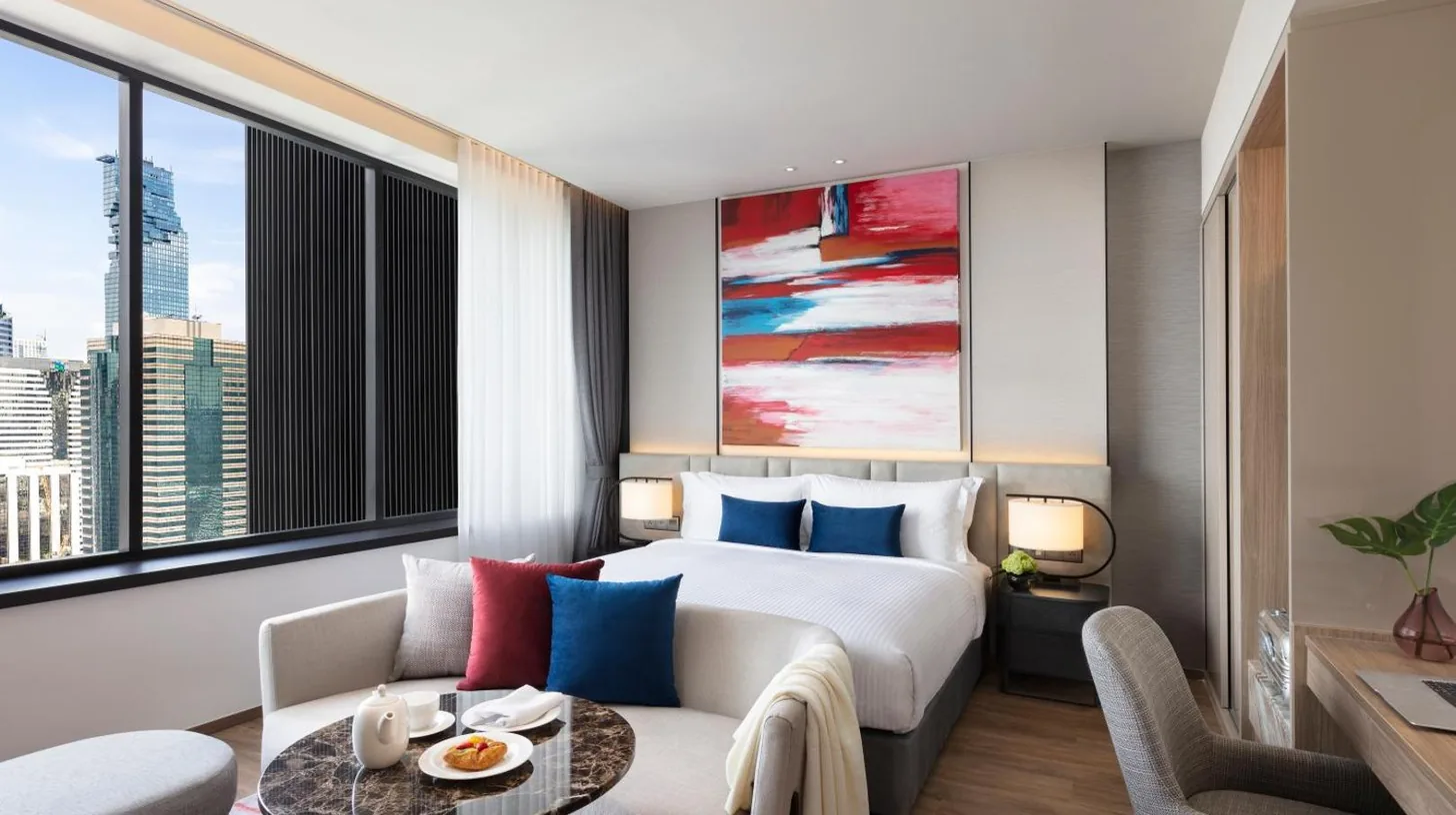 a hotel room with a bed and a couch at Ascott Embassy Sathorn Bangkok in Bangkok