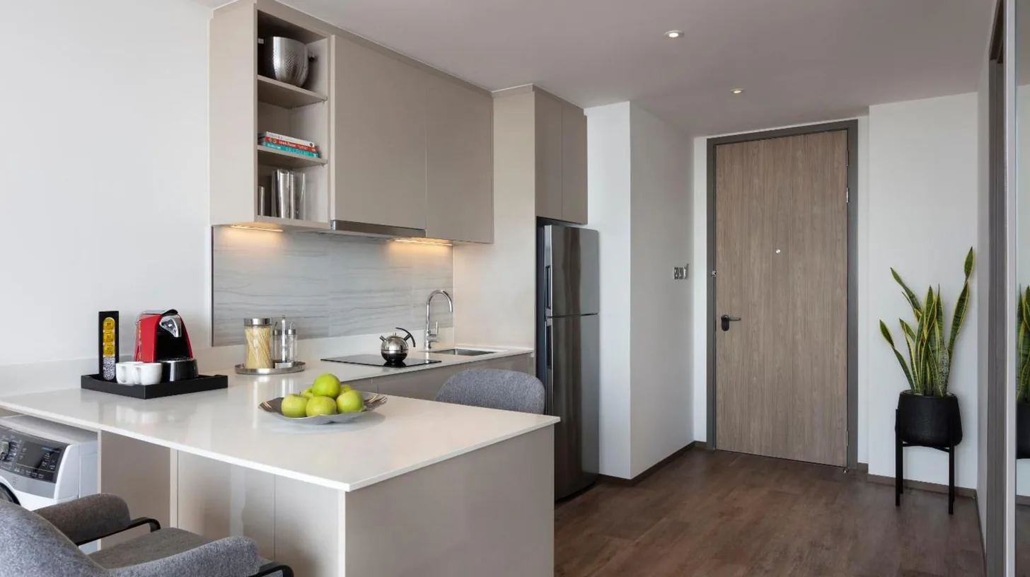 a kitchen and living room with a white counter top at Ascott Embassy Sathorn Bangkok in Bangkok