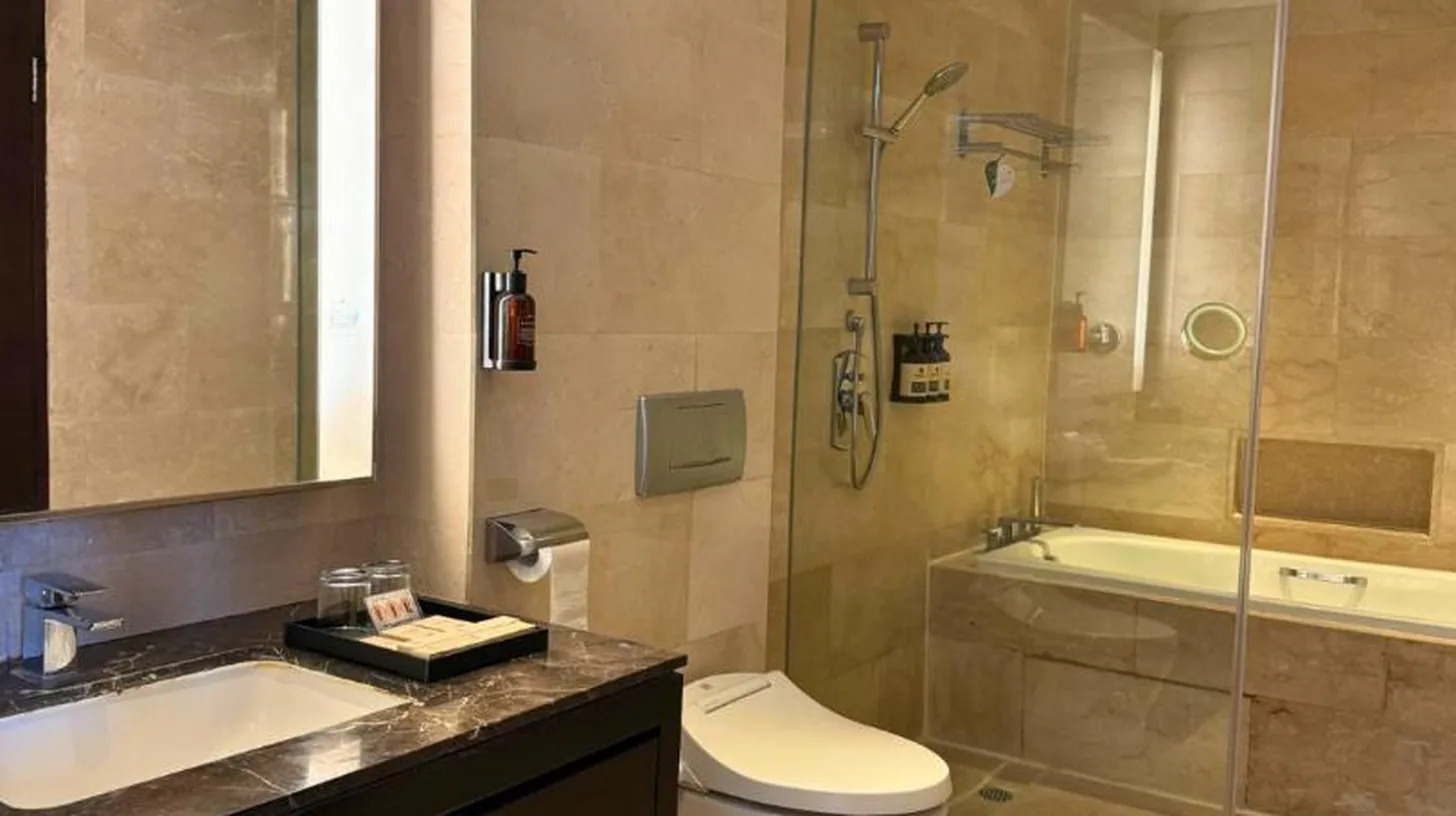 a bathroom with a toilet and a glass shower at Ascott Kuningan Jakarta in Jakarta
