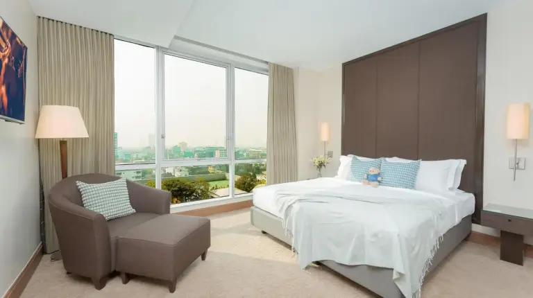 una habitación con una cama grande y una silla en Ascott Sathorn Bangkok en Bangkok