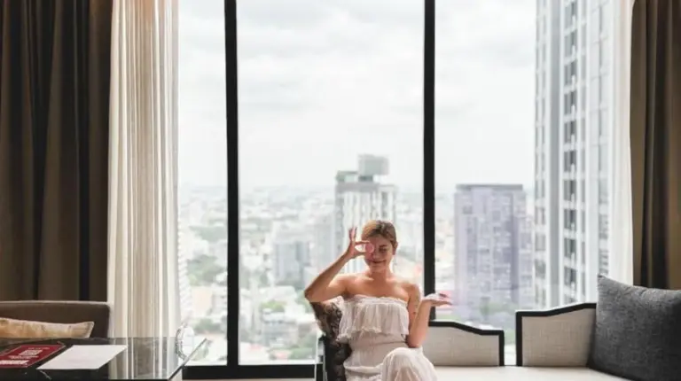 a woman sitting in a chair in a room with a window at Ascott Thonglor Bangkok in Bangkok