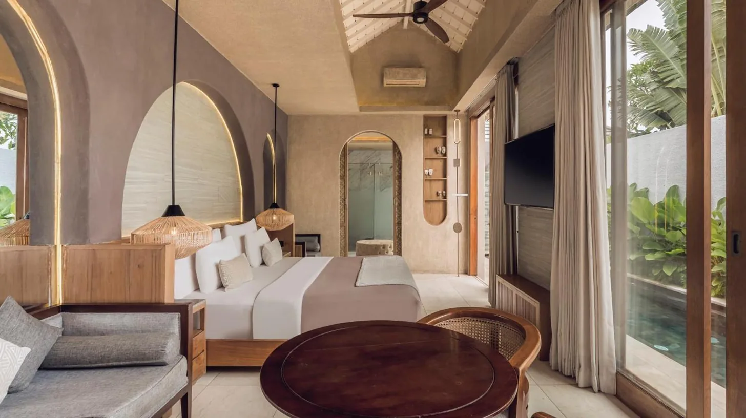 a bedroom with a large bed and two chairs at Astera Villa Seminyak by Ini Vie Hospitality in Seminyak