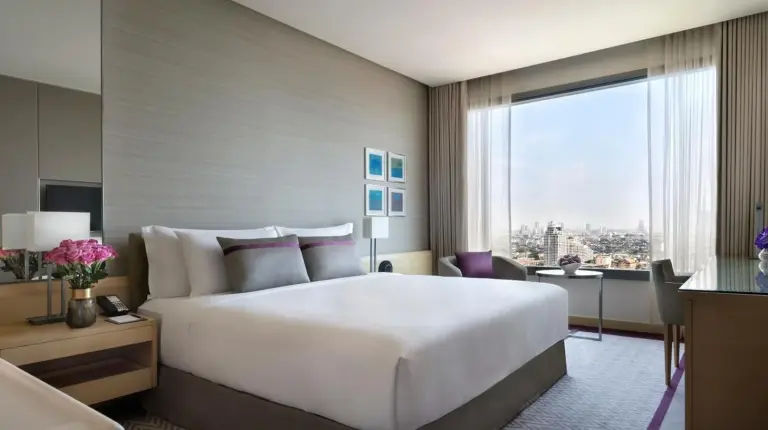 a hotel room with a large bed and a window at Avani Plus Riverside Bangkok Hotel in Bangkok