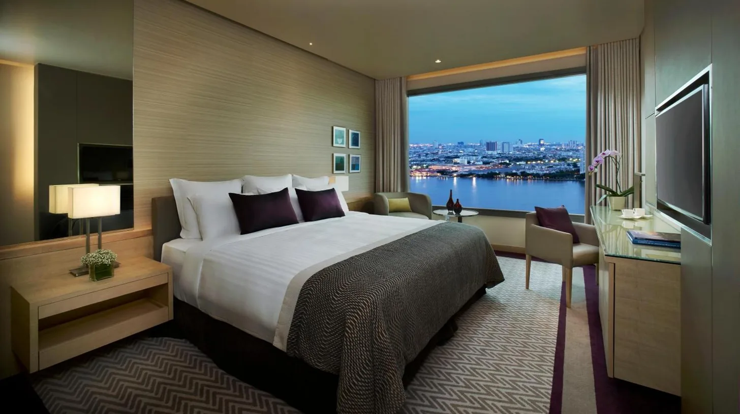 a hotel room with a large bed and a large window at Avani Plus Riverside Bangkok Hotel in Bangkok