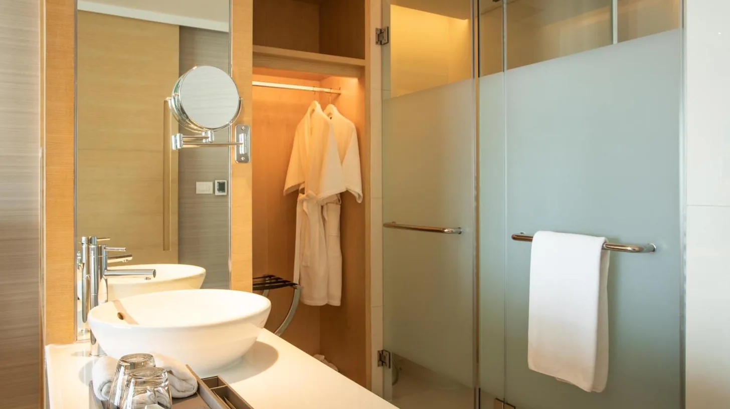 a bathroom with a sink and a glass shower at Avani Plus Riverside Bangkok Hotel in Bangkok