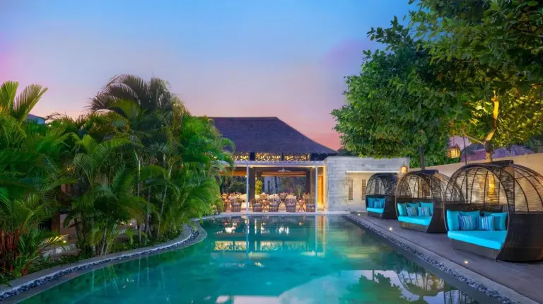 a swimming pool with blue chairs next to a house at Avani Seminyak Bali Resort in Seminyak