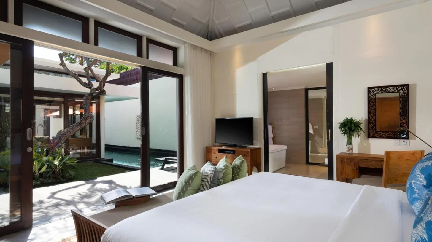 a bedroom with a large bed and a living room at Avani Seminyak Bali Resort in Seminyak