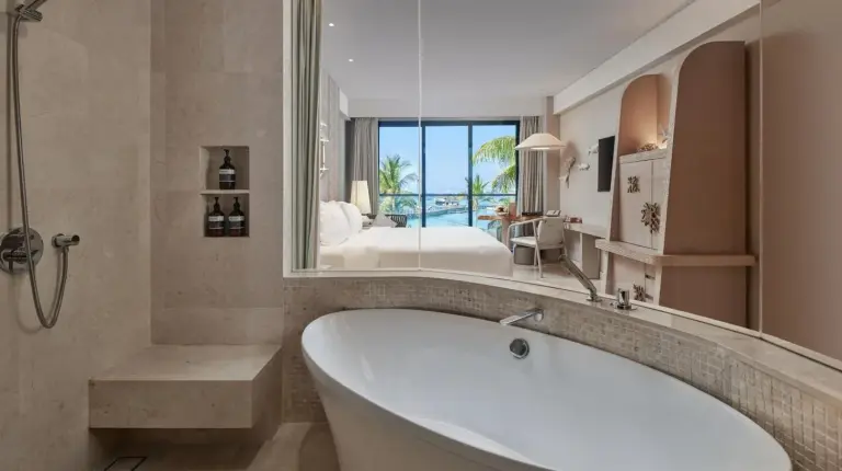a bath tub in a bathroom with a bedroom at AYANA Komodo Waecicu Beach in Labuan Bajo