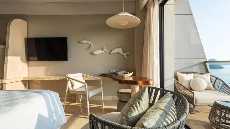 a room with a bed and a table and a tv at AYANA Komodo Waecicu Beach in Labuan Bajo