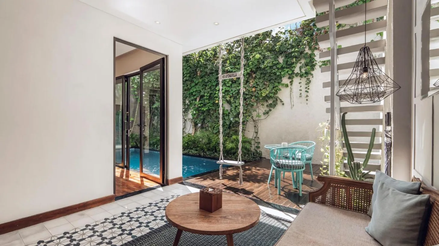 eine Gruppe von Personen sitzt an einem Tisch auf einem Balkon bei Ayona Villa Seminyak by Ini Vie Hospitality in Seminyak