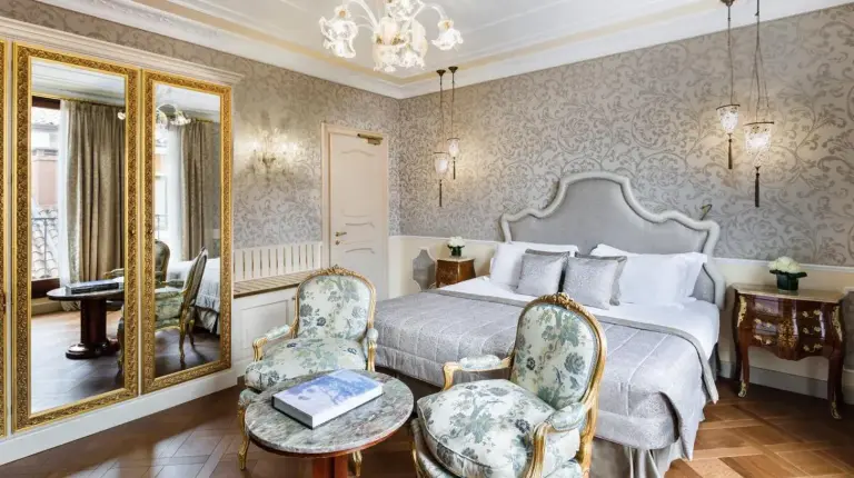 a bedroom with a large bed and a desk and a desk at Baglioni Hotel Luna - The Leading Hotels of the World in Venice