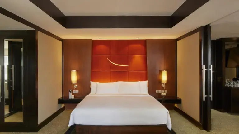 una habitación con una cama grande y dos mesas en Banyan Tree Bangkok en Bangkok