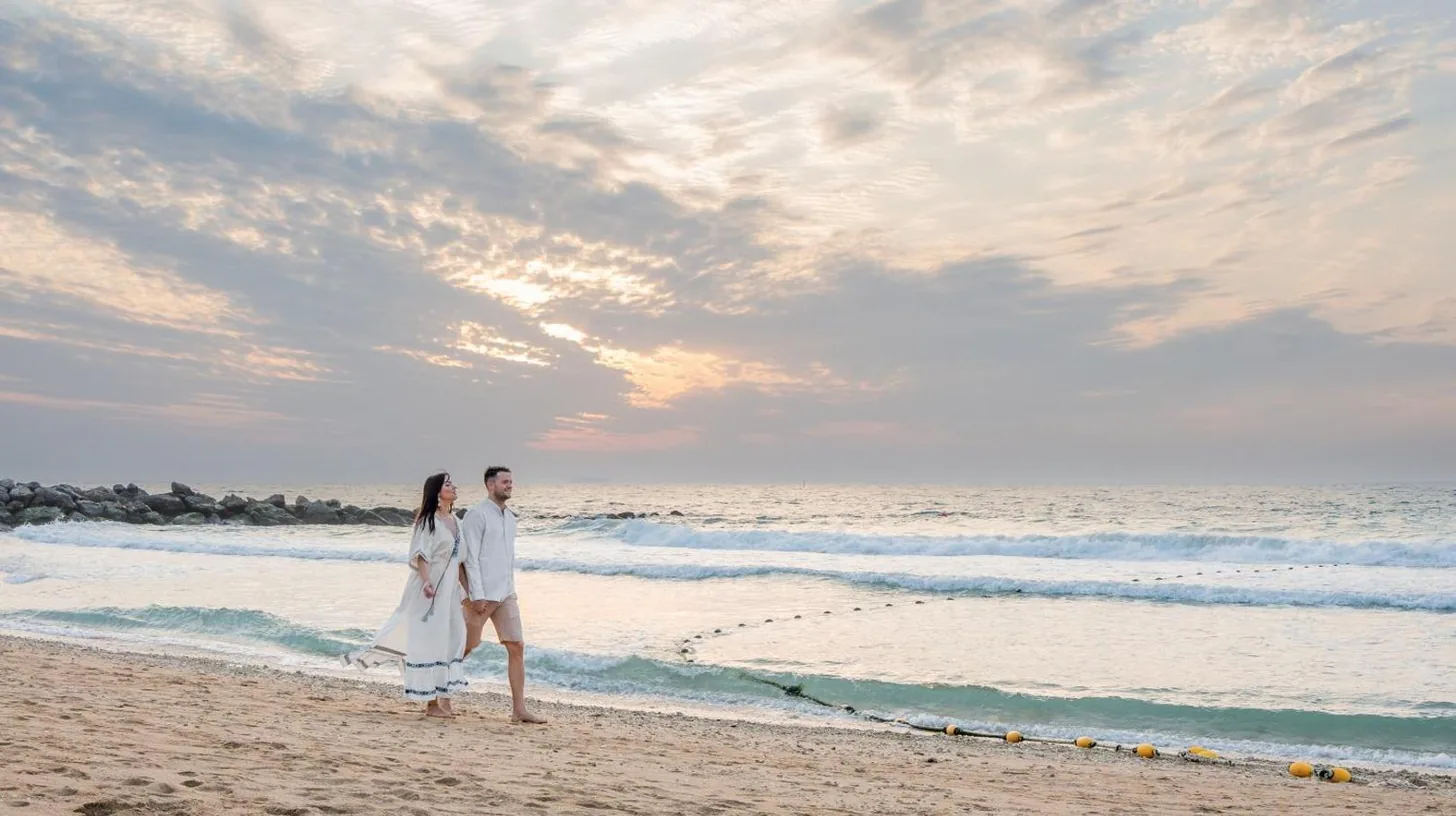 un homme et une femme marchant sur la plage à Banyan Tree Dubai at Bluewaters à Dubaï