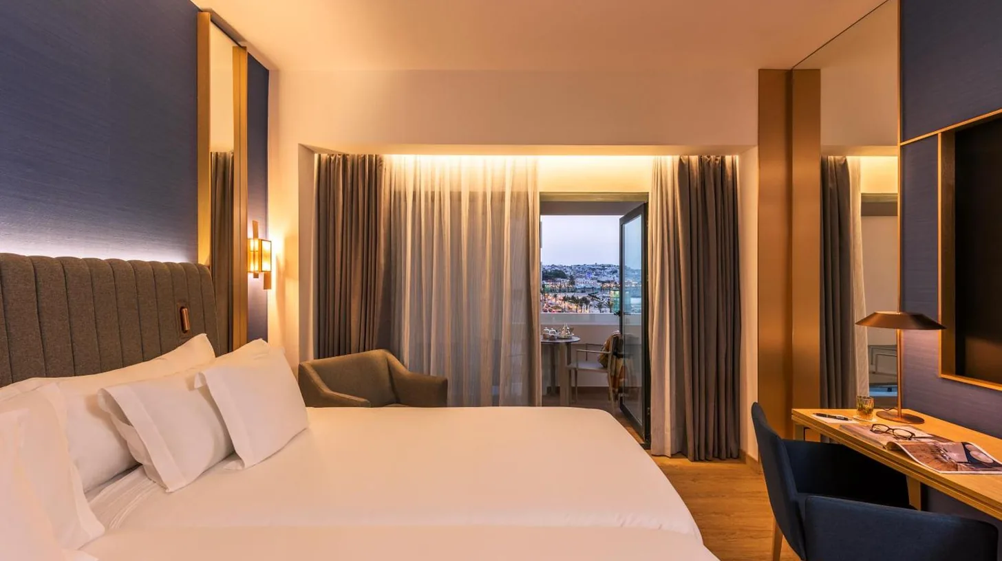 une chambre d’hôtel avec un lit blanc et un bureau à Barceló Tanger à Tanger