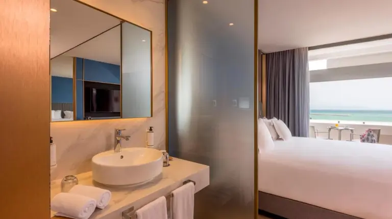 une salle de bain avec un lavabo, un lit et un miroir à Barceló Tanger à Tanger