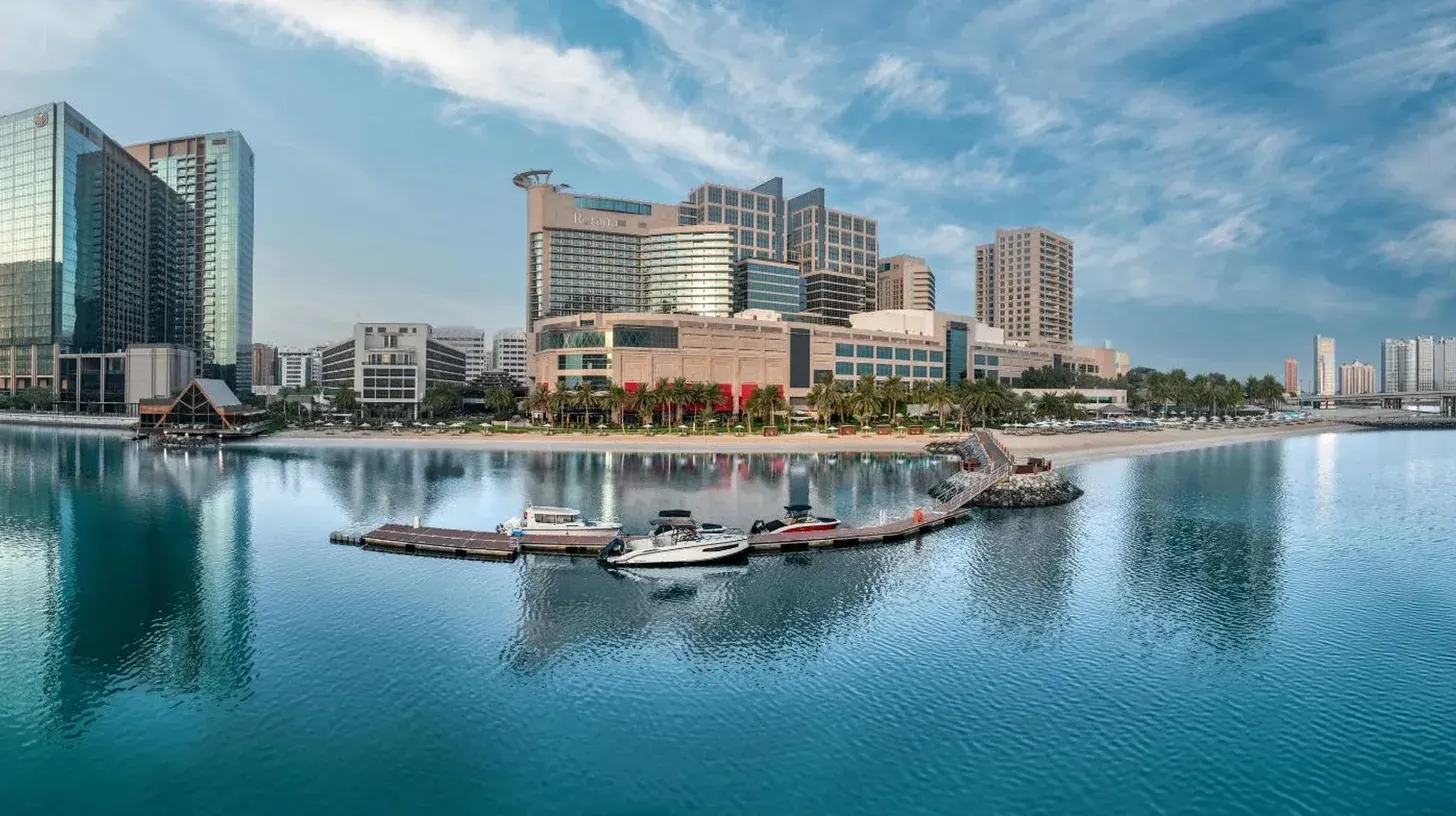 a group of boats docked in a river with a city at Beach Rotana – All Suites in Abu Dhabi