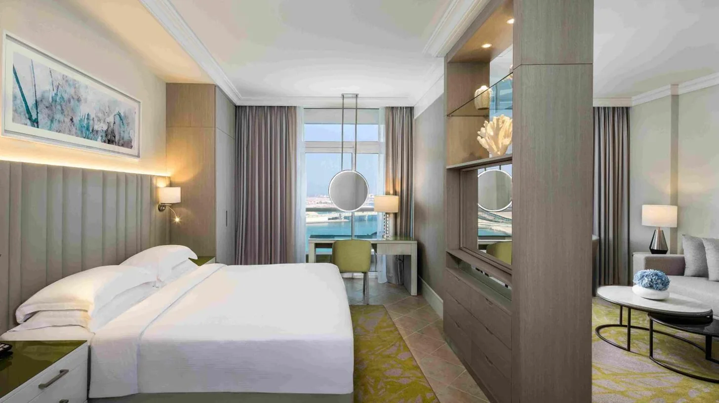 a bedroom with a large bed and a living room at Beach Rotana – All Suites in Abu Dhabi