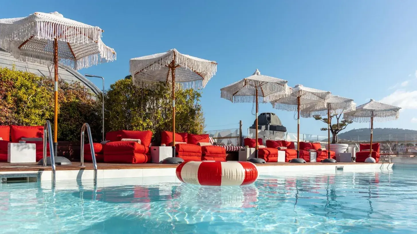 a swimming pool with red chairs and umbrellas at Boscolo Nice Hotel & Spa in Nice