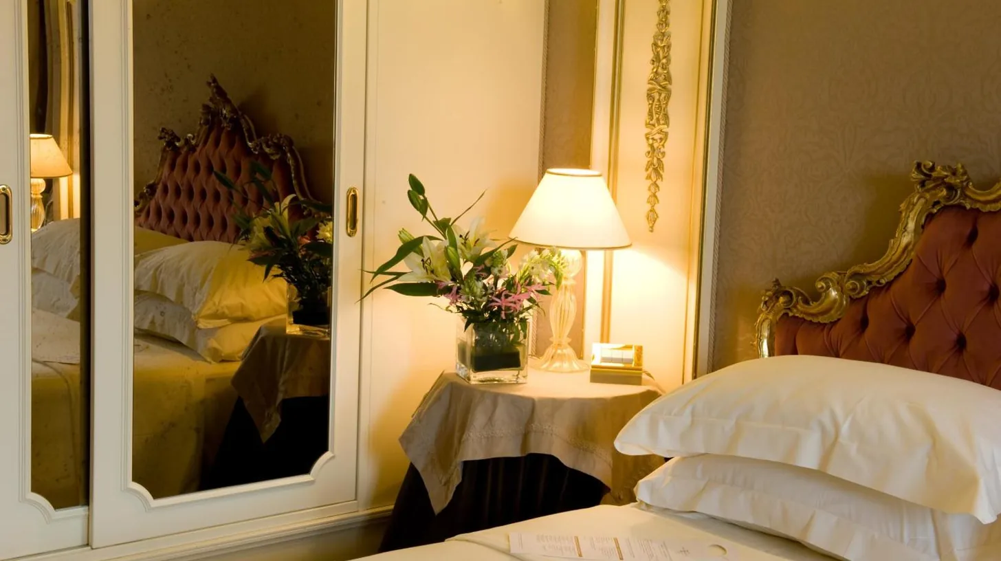 a bedroom with a mirror next to a bed at Ca' Sagredo Hotel in Venice