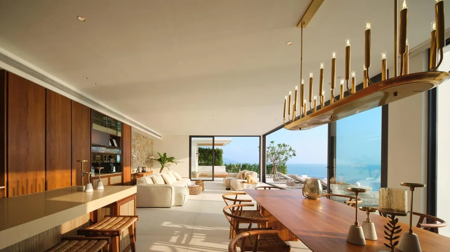 a kitchen and living room with a long table and chairs at Cape Azure Resort Samui by Thalsea in Plai Laem