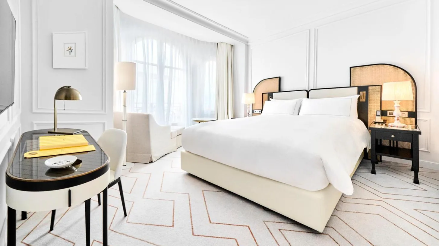a bedroom with a bed and a table with a lamp at Carlton Cannes