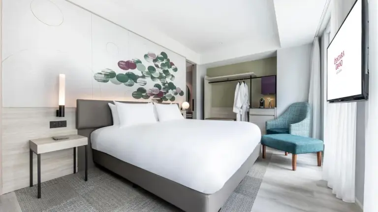 a bedroom with a large white bed and a blue chair at Centara Grand Hotel Osaka in Osaka