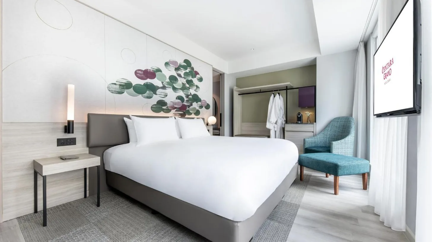a bedroom with a large white bed and a blue chair at Centara Grand Hotel Osaka in Osaka